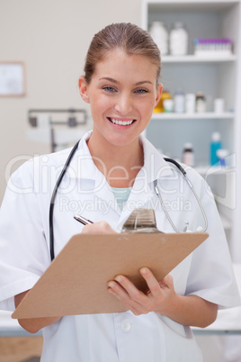 Smiling doctor taking notes on clipboard