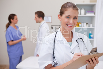 Smiling doctor writing on clipboard