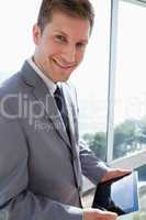 Businessman standing in front of the window with his tablet