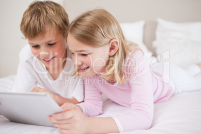 Smiling siblings using a tablet computer