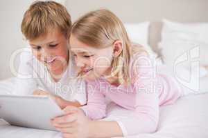 Smiling siblings using a tablet computer