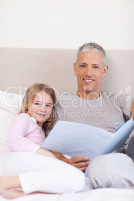 Portrait of a father reading a story to his daughter
