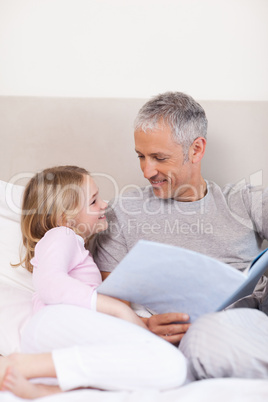Portrait of a smiling father reading a story to his daughter