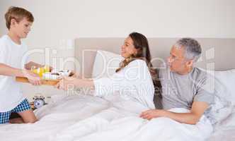 Boy serving breakfast to his parents