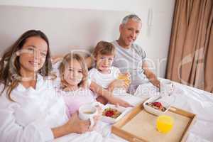 Smiling family having breakfast in a bedroom