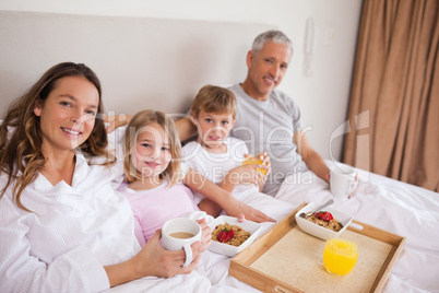Happy family having breakfast in a bedroom