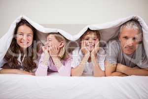 Happy family lying under a duvet