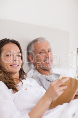 Portrait of a woman reading a book while her husband is reading