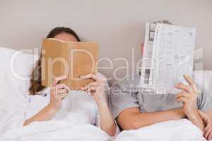 Woman reading a book while her companion is reading a newspaper