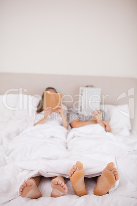 Portrait of woman reading a book while her companion is reading