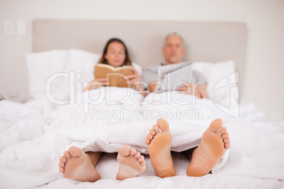 Woman reading a book while her companion is reading the news