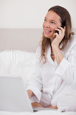 Portrait of a woman using a laptop while making a phone call