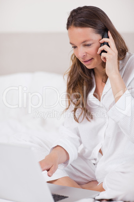 Portrait of a quiet woman using a laptop while making a phone ca