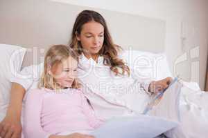 Girl reading a book with her mother