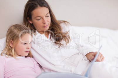 Little girl reading a book with her mother