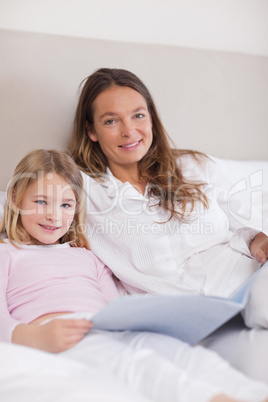 Portrait of a smiling girl reading a book with her mother