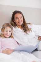 Portrait of a smiling girl reading a book with her mother