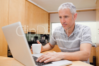 Man using a laptop while drinking coffee Man using a laptop while drinking coffee