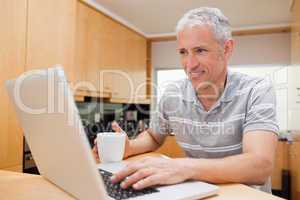 Man using a laptop while drinking tea