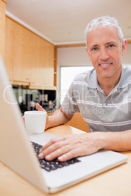 Portrait of a man using a notebook while drinking tea