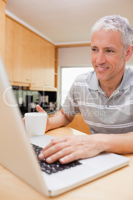 Portrait of a man using a notebook while drinking coffee