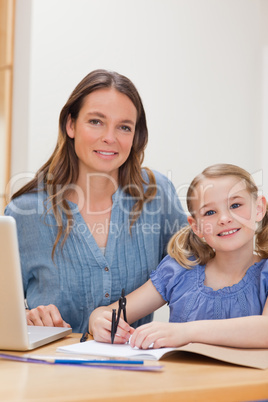 Portrait of a beautiful woman helping her daughter doing her hom
