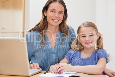 Beautiful woman helping her daughter doing her homework