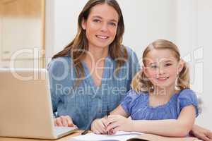 Beautiful woman helping her daughter doing her homework