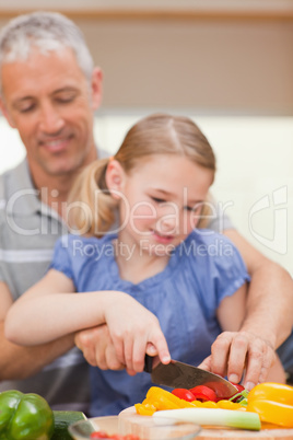 Portrait of a father slicing pepper with his daughter