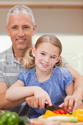 Portrait of a man slicing pepper with his daughter