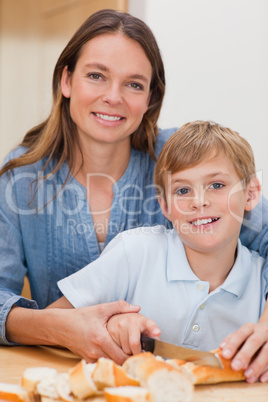 Portrait of a mother slicing bread with her son