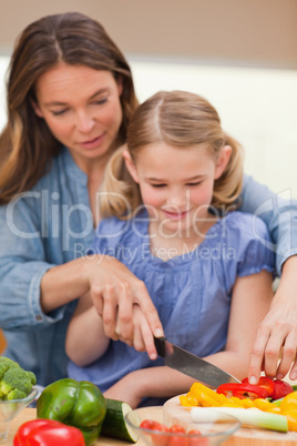 Portrait of a mother slicing pepper with her daughter