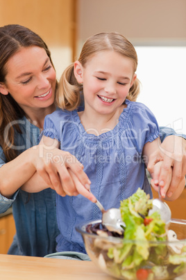 Portrait of a mother preparing a salad with her daughter