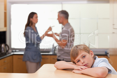 Sad little boy hearing his parents arguing