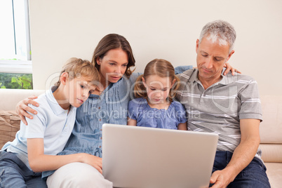 Family sitting on a sofa using a laptop