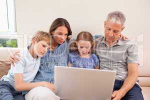 Family sitting on a sofa using a laptop