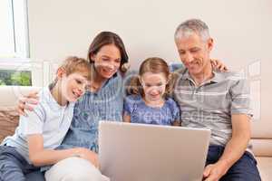 Family sitting on a sofa using a notebook