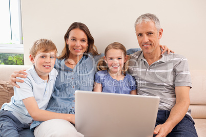 Smiling family sitting on a sofa using a notebook