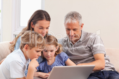 Happy family sitting on a sofa using a notebook