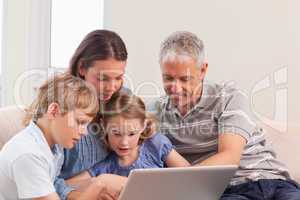 Happy family sitting on a sofa using a laptop