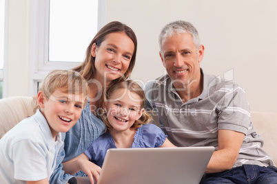 Happy family sitting on a couch using a laptop