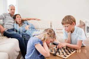 Children playing chess in front of their parents