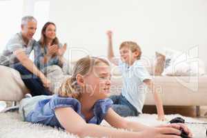 Cute children playing video games with their parents on the back