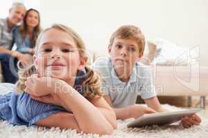Happy siblings using a tablet computer with their parents on the