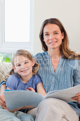 Portrait of a mother reading a book to her daughter