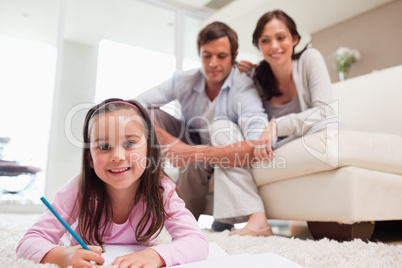 Girl drawing with her parents in the background