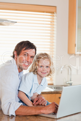 Portrait of a boy and his father using a notebook together