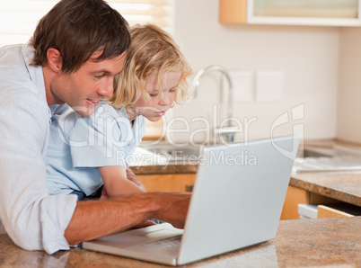 Cute boy and his father using a laptop together