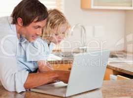 Cute boy and his father using a laptop together