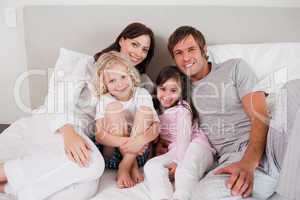 Smiling family posing on a bed